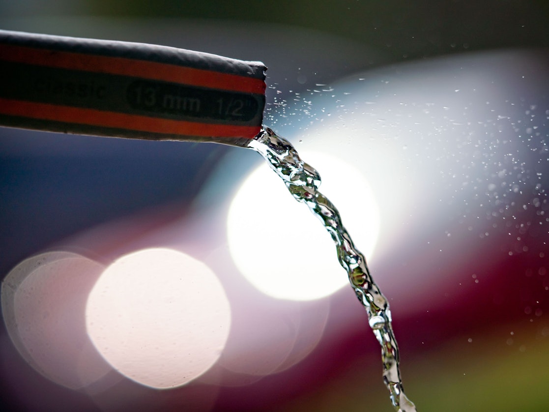 Wasser fließt in einem Frankfurter Vorgarten aus einem Gartenschlauch.