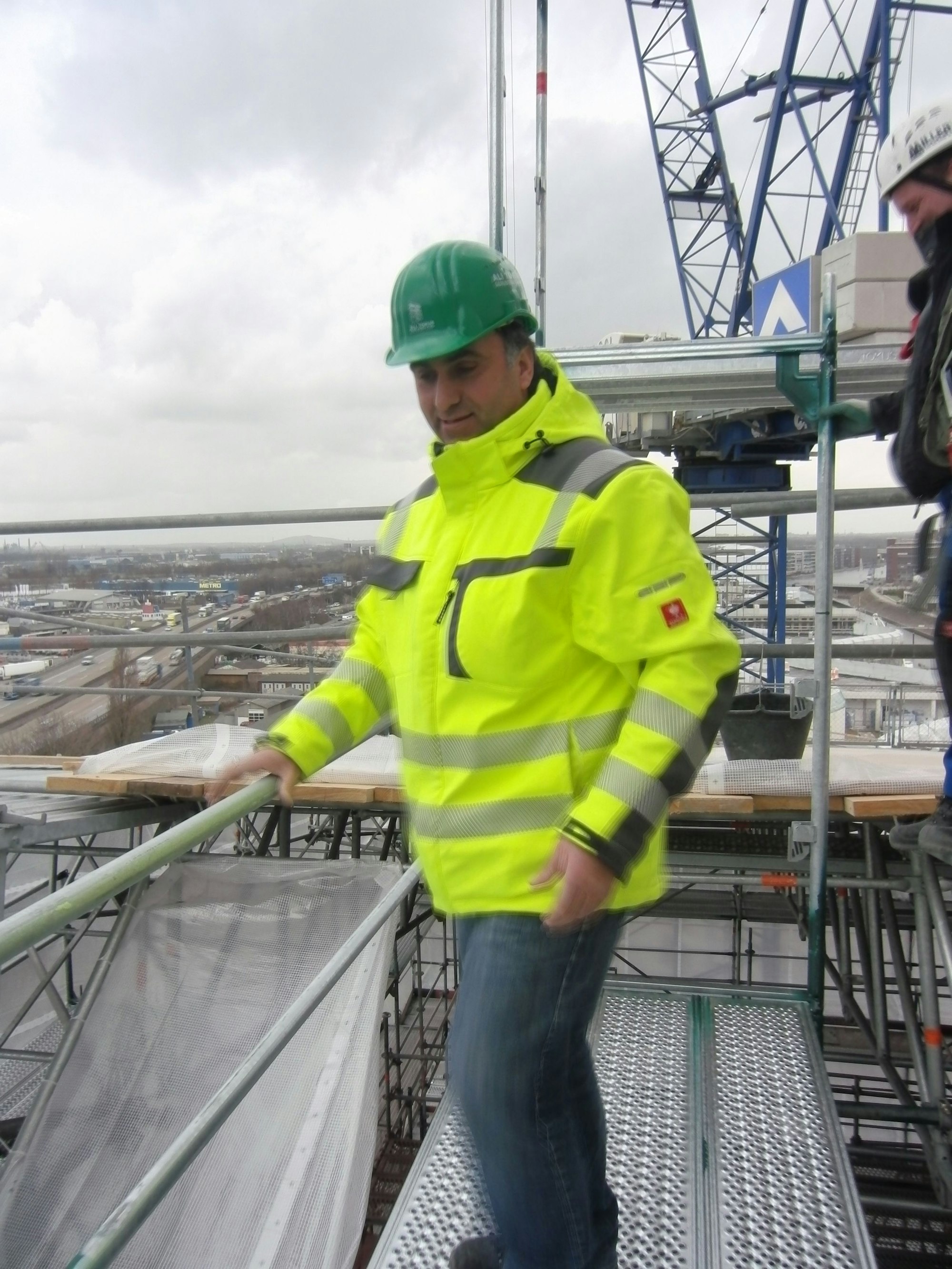 Ali Tokus steht auf einem Baugerüst.