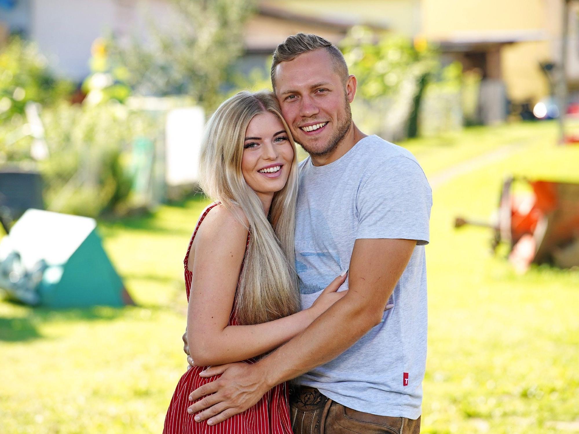 Das Foto zeigt die „Bauer sucht Frau“-Stars Antonia Hemmer und Patrick Romer, die vor einer grünen Wiese posieren.
