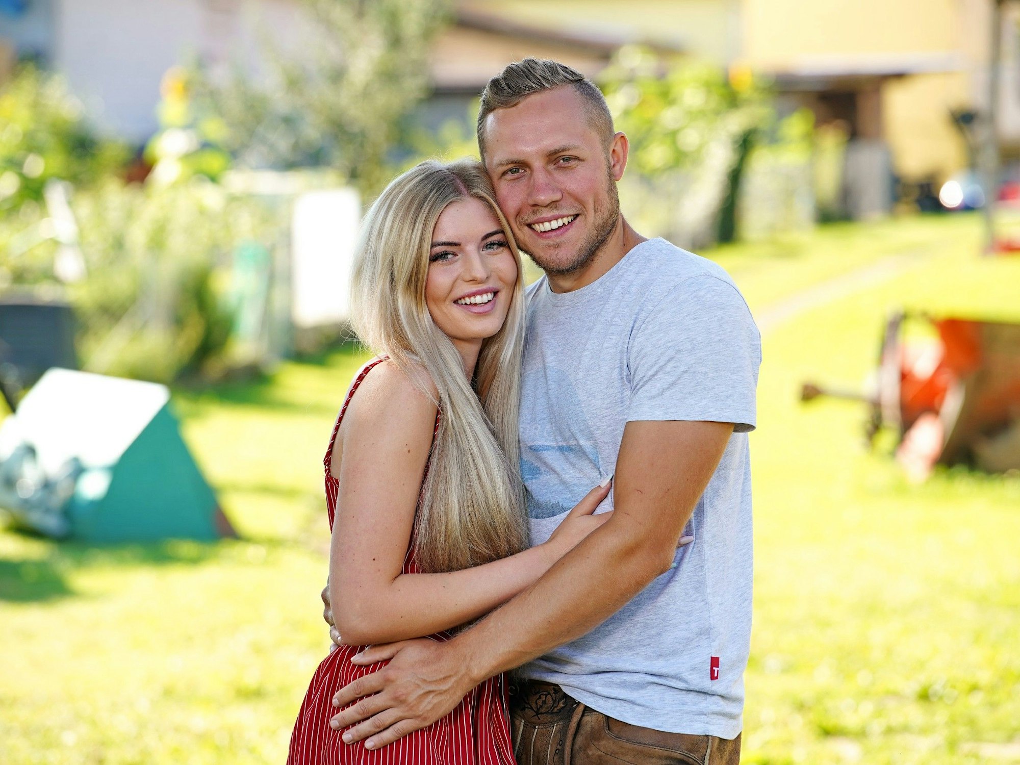 Das Foto zeigt die „Bauer sucht Frau“-Stars Antonia Hemmer und Patrick Romer, die vor einer grünen Wiese posieren.