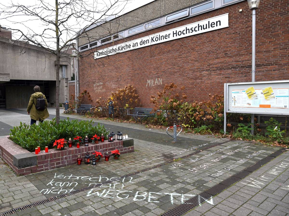Blumen und Kerzen stehen neben einem Schriftzug auf dem Boden.