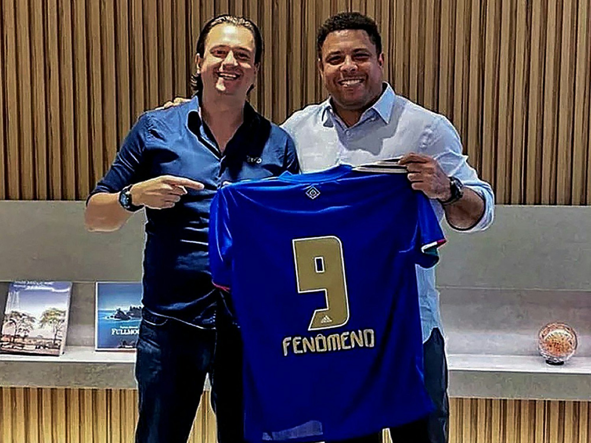 Sergio Santos Rodrigues und Ronaldo Nazario halten ein blaues Trikot mit der Rückennummer 9 und dem Namen „Fenomeno“, Ronaldos Spitznamen.