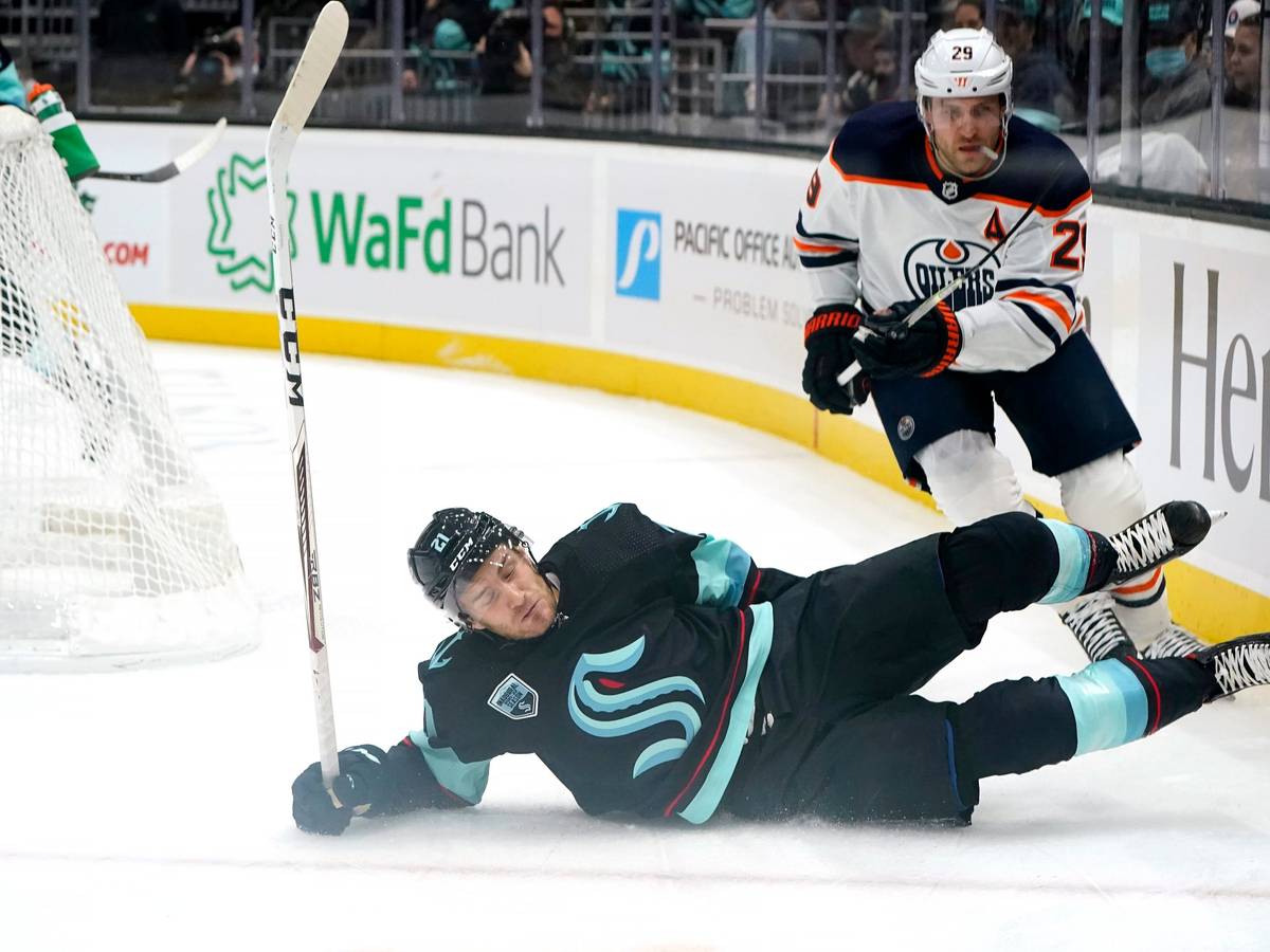 Seattle Kraken's Alex Wennberg, left, skids across the ice in front of Edmonton Oilers' Leon Draisaitl in the first period of an NHL hockey game Saturday, Dec. 18, 2021, in Seattle. (AP Photo/Elaine Thompson)