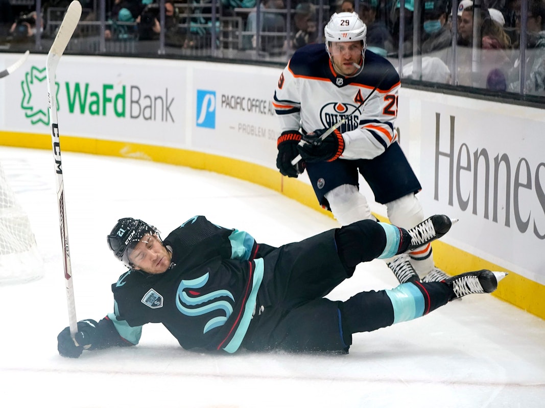 Seattle Kraken's Alex Wennberg, left, skids across the ice in front of Edmonton Oilers' Leon Draisaitl in the first period of an NHL hockey game Saturday, Dec. 18, 2021, in Seattle. (AP Photo/Elaine Thompson)