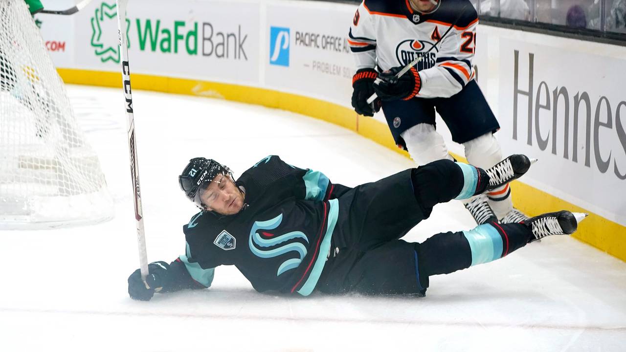 Seattle Kraken's Alex Wennberg, left, skids across the ice in front of Edmonton Oilers' Leon Draisaitl in the first period of an NHL hockey game Saturday, Dec. 18, 2021, in Seattle. (AP Photo/Elaine Thompson)