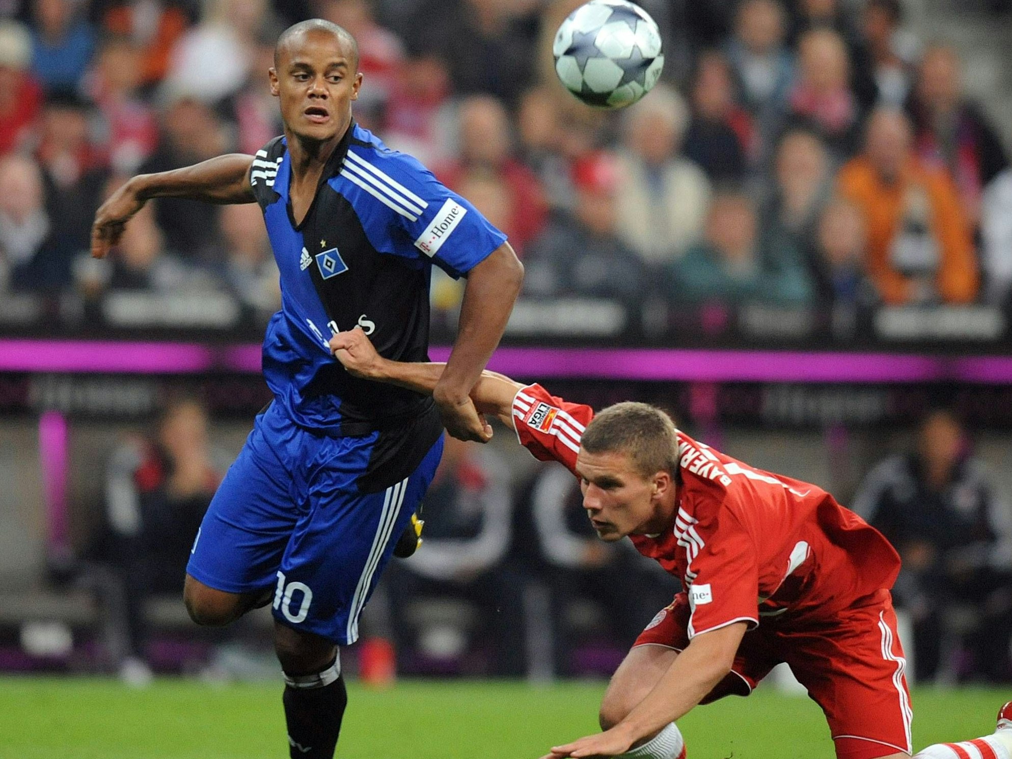 Lukas Podolski fällt zu Boden, Vincent Kompany kann das Gleichgewicht halten.