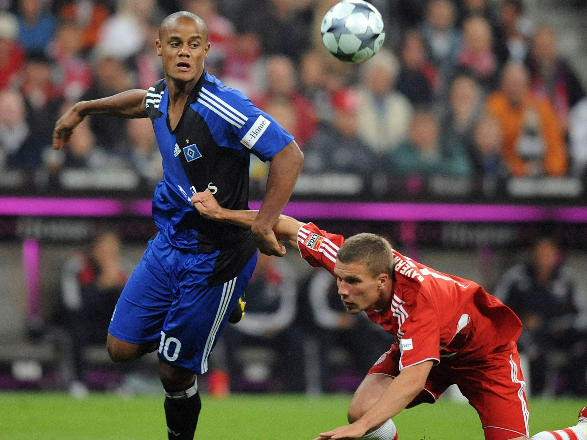 Lukas Podolski fällt zu Boden, Vincent Kompany kann das Gleichgewicht halten.