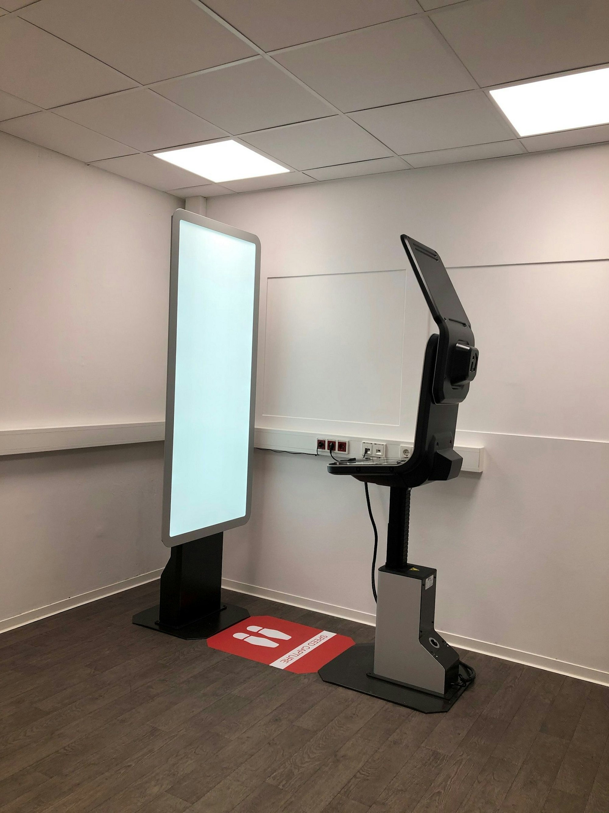 Seitenansicht des neuen Self-Service-Terminals mit Bildschirm, Schaltfläche und Fotowand