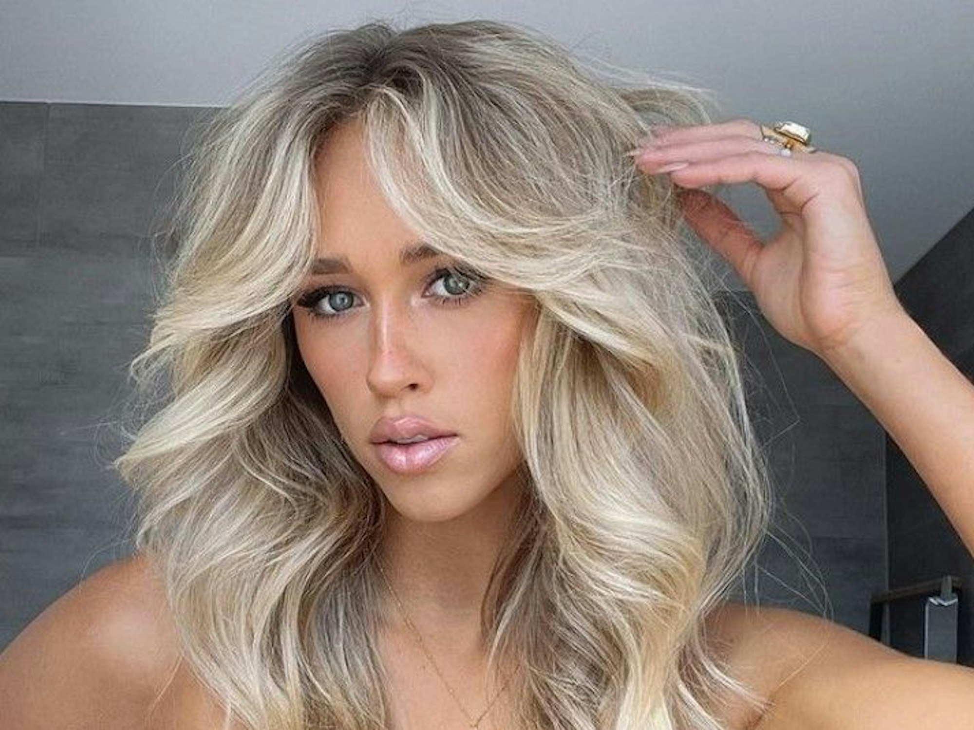 Auf dem Foto sieht man Zoe Creed, die Haare aufwendig gestylt und das Gesicht geschminkt.