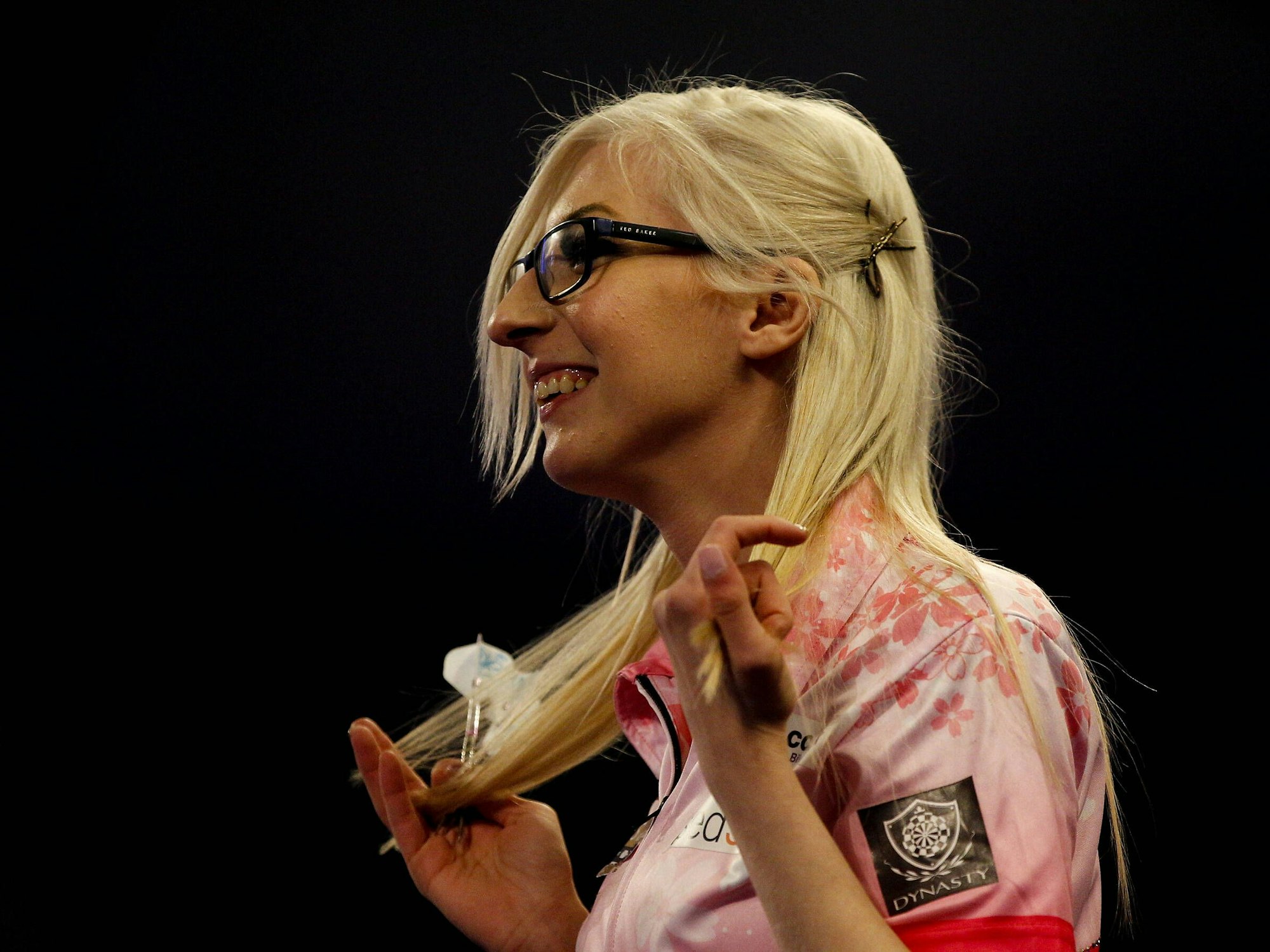 Fallon Sherrock hält ihre Pfeile in der rechten Hand und lacht.