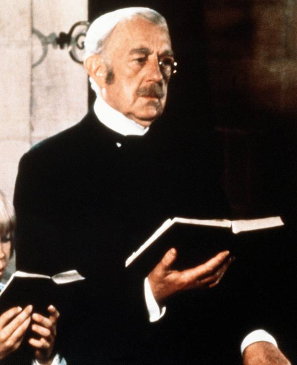 Der alte Earl of Dorincourt (Alec Guinness) steht neben seinem Enkel Ceddie (Ricky Schroder). Beide halten ein Gesangsbuch in der Hand.