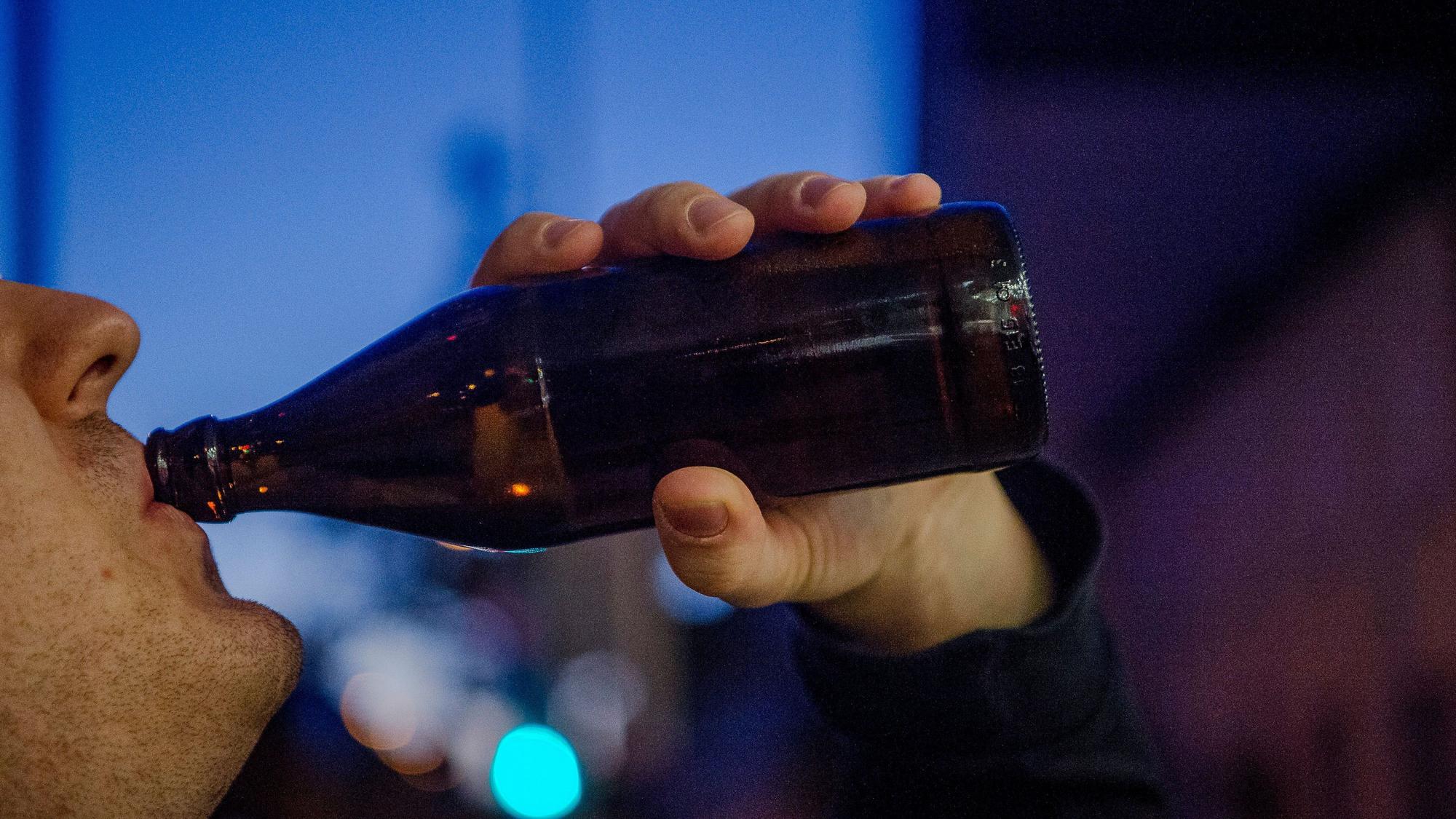 Ein Mann trinkt abends eine Flasche Bier