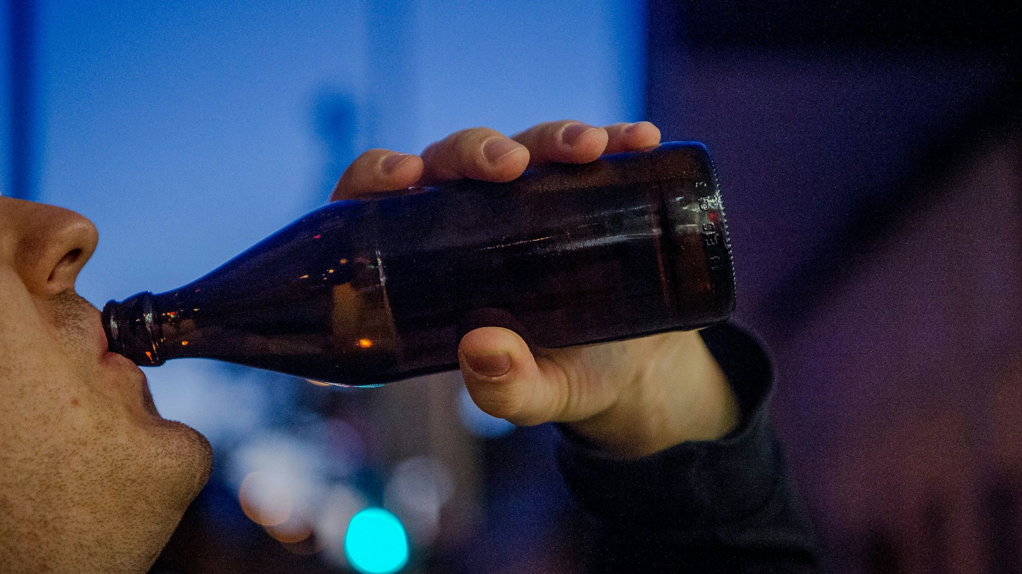 Ein Mann trinkt abends eine Flasche Bier