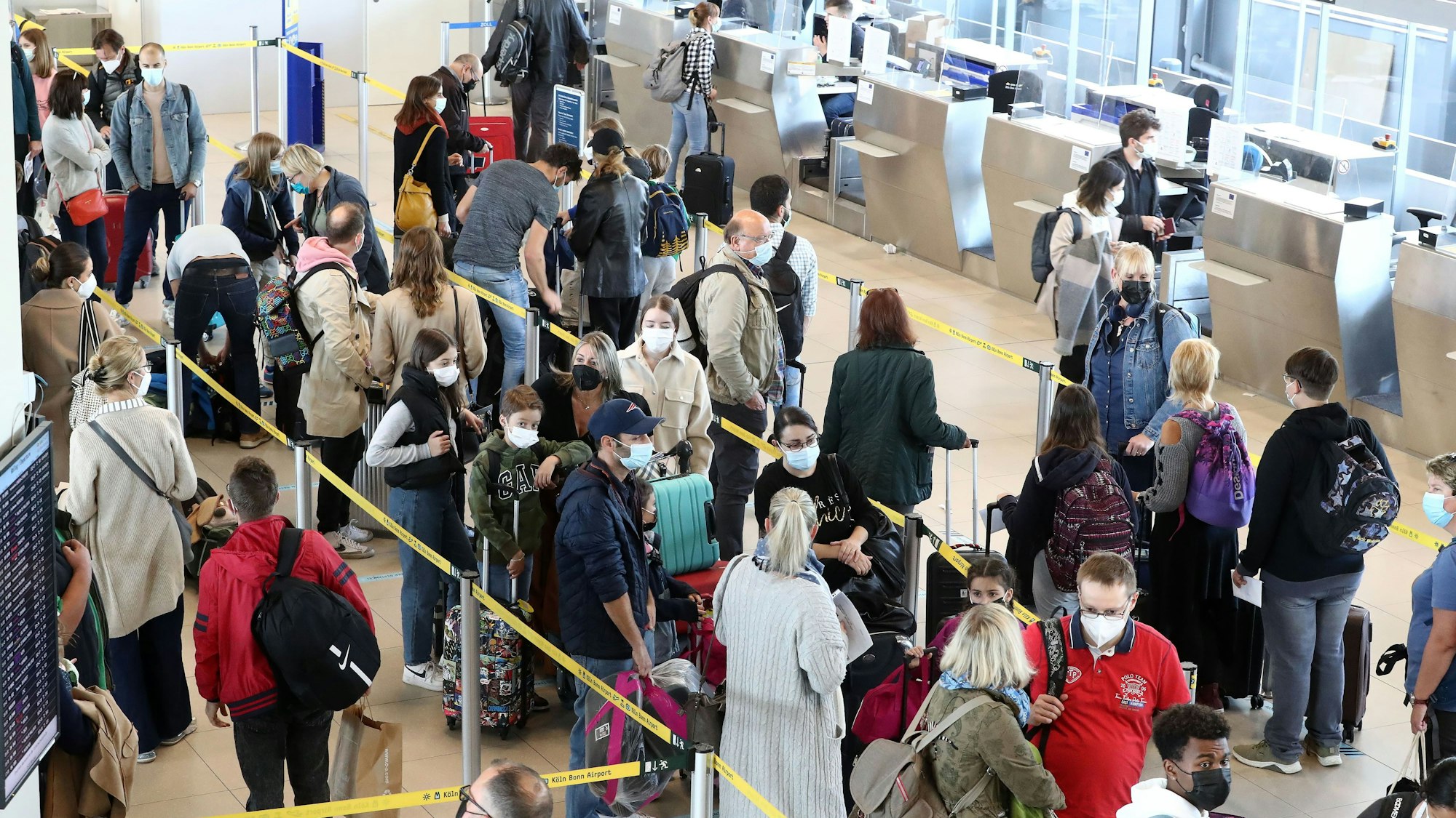 Viele Menschen stehen in einer Schlange vor einem Flughafenschalter.