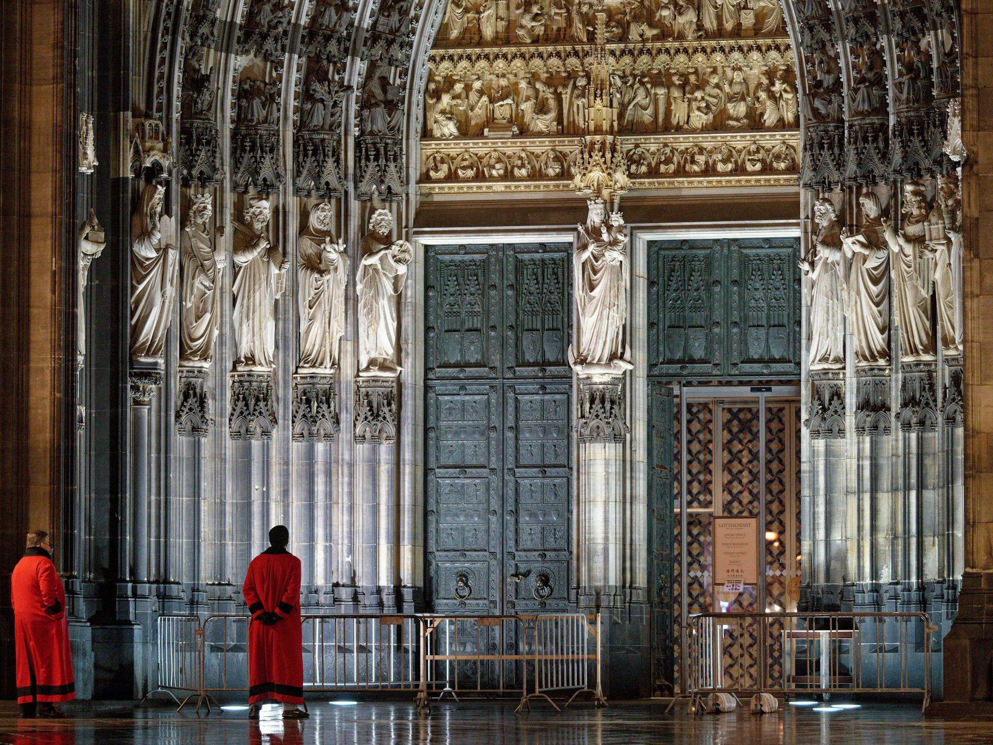 Zwei Domschweizer stehen am frühen Morgen auf der Domplatte vor dem Eingang Hauptportal des Doms.