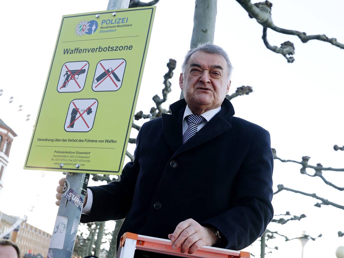 Düsseldorf: NRW-Innenminister Herbert Reul (CDU) befestigt auf der Düsseldorfer Rheinufer Promenade ein Schild zur Waffenverbotszone.