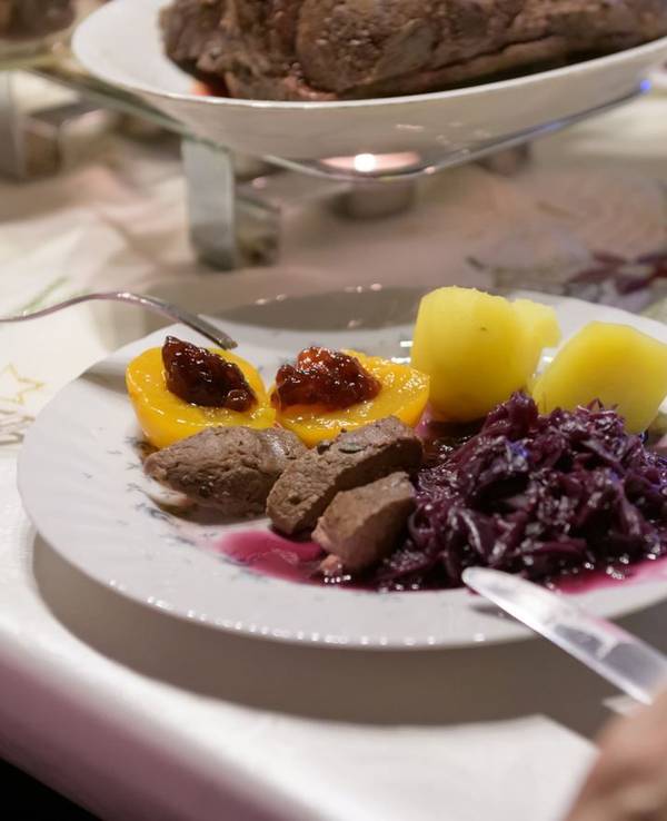 Hamburg: Damhirsch-Rücken mit Kartoffeln und Rotkohl sowie Preiselbeergelee auf Aprikosen liegen verzehrfertig auf einem Teller an Heiligabend.
