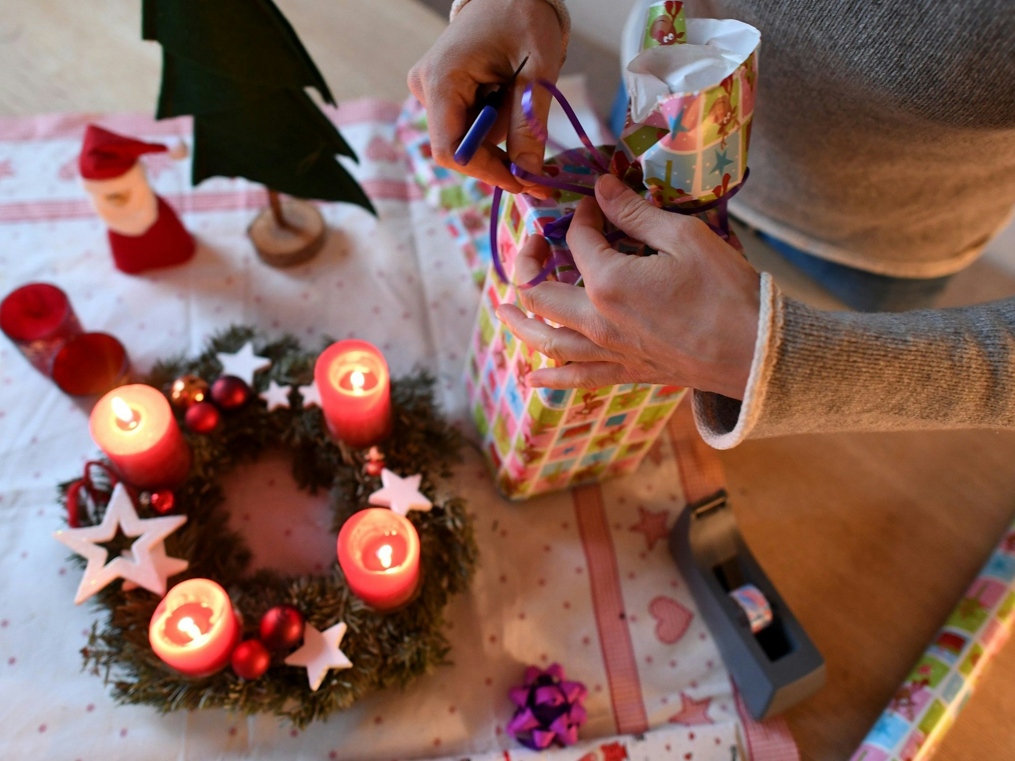 Eine Frau packt in unserem Symbolbild am vierten Advent Weihnachtsgeschenke ein. Wir erklären, welche Corona-Regeln an Weihnachten in NRW gelten.