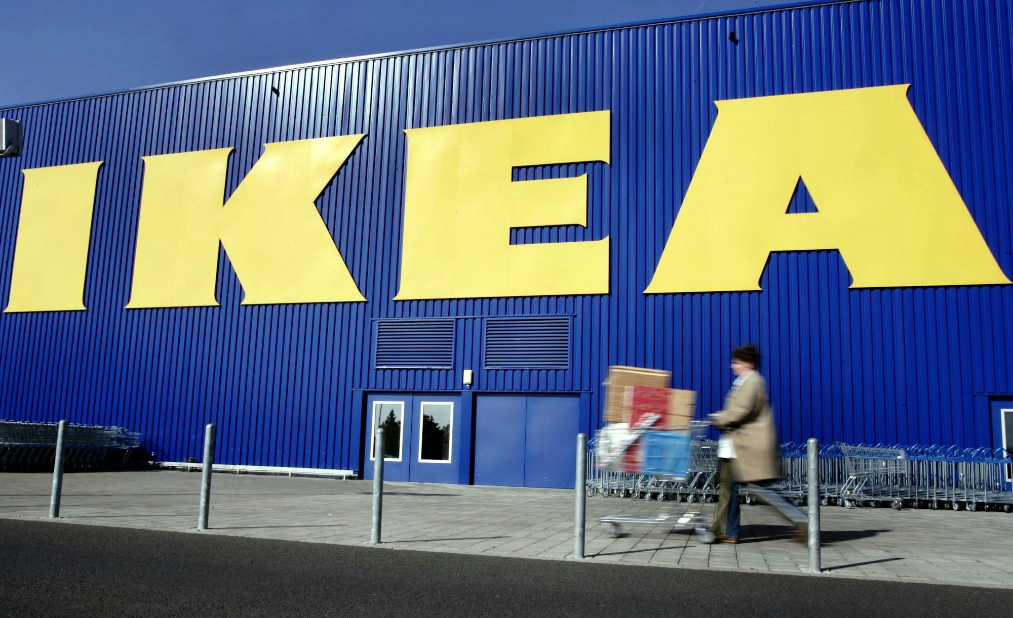 Eine Kundin des Möbelhauses Ikea schiebt auf dem Gelände der Filiale in Wallau bei Wiesbaden ihren Einkaufswagen an der Fassade des Einrichtungshauses vorbei.