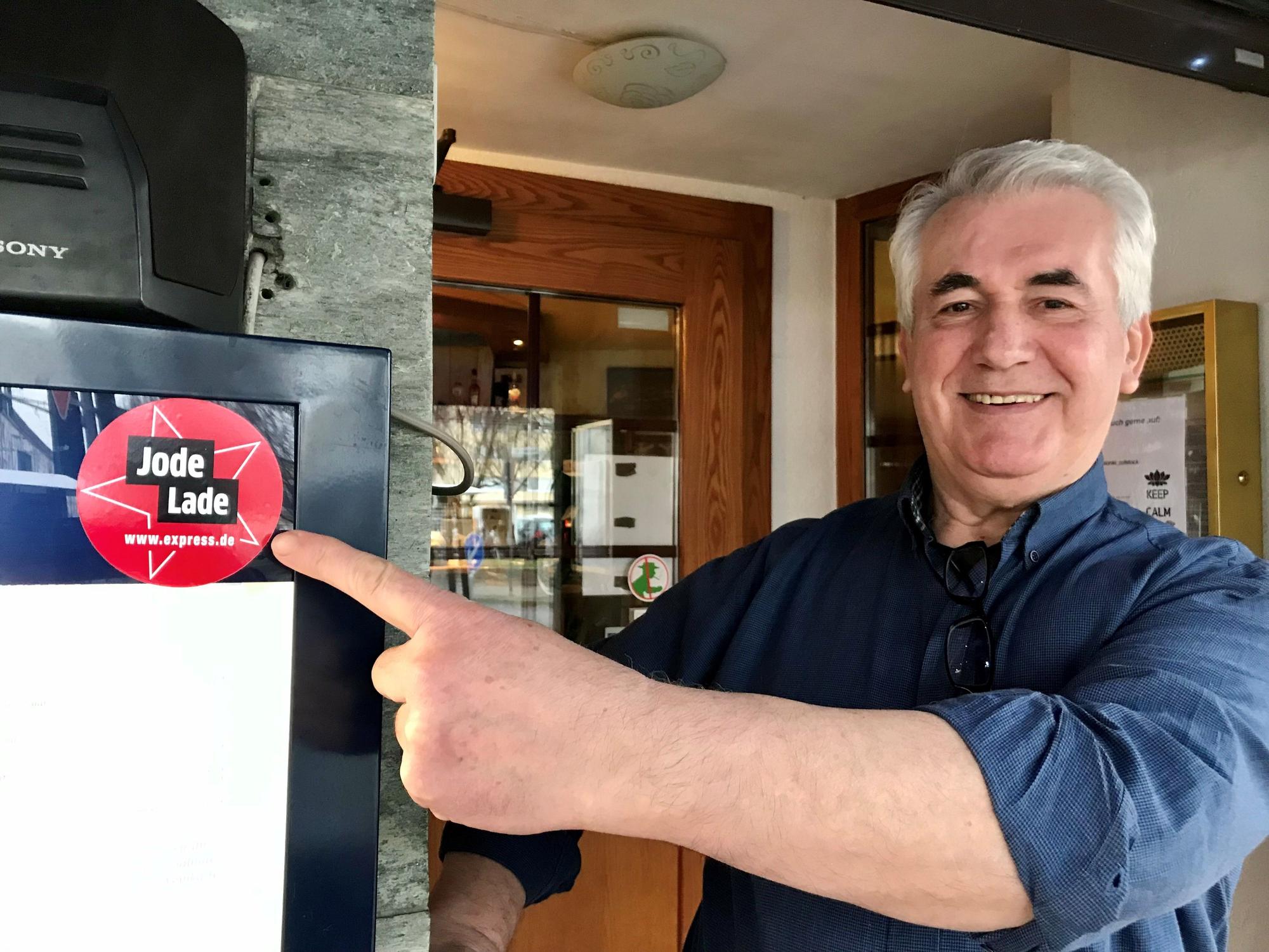 Christos Spanos zeigt vor seinem Lokal auf den Aufkleber.