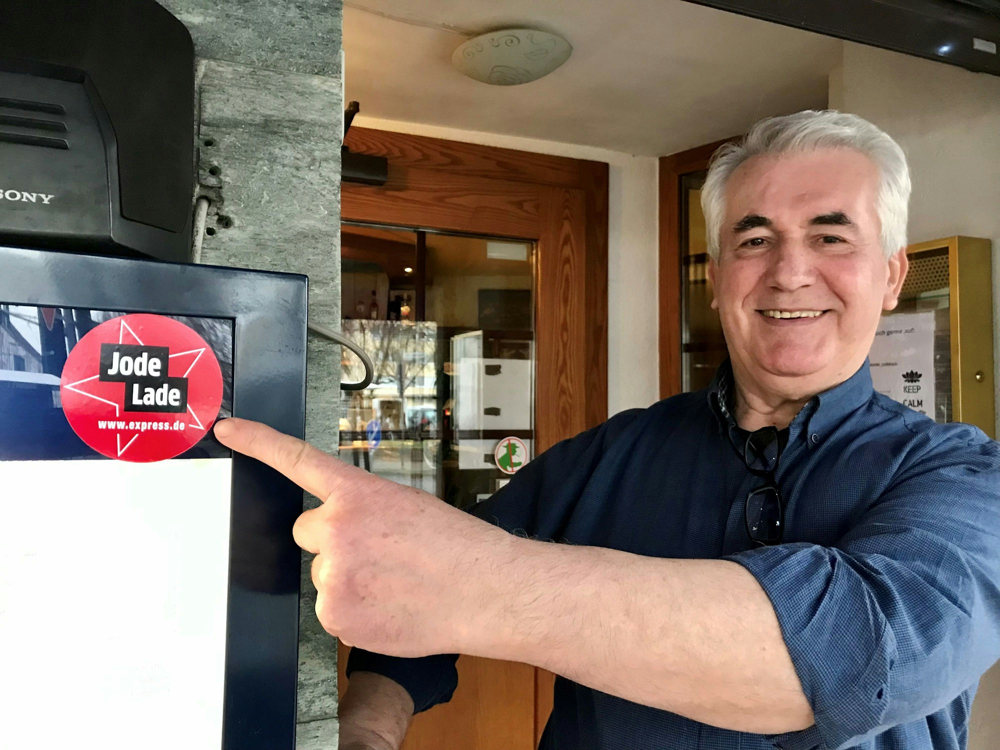 Christos Spanos zeigt vor seinem Lokal auf den Aufkleber.