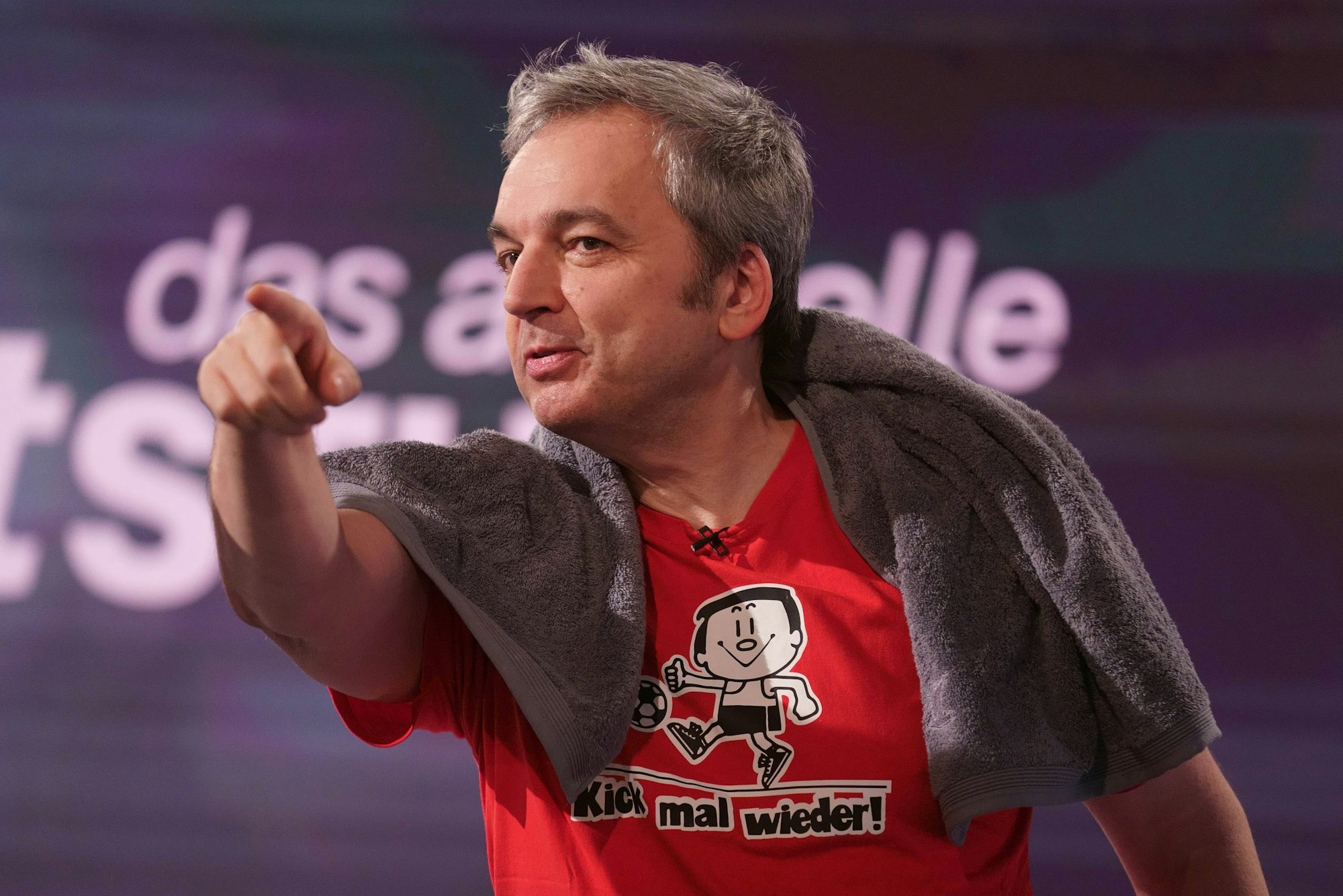 Arnd Zeigler hat ein Handtuch um die Schultern geworfen und zeigt mit dem Zeigefinger nach vorne.