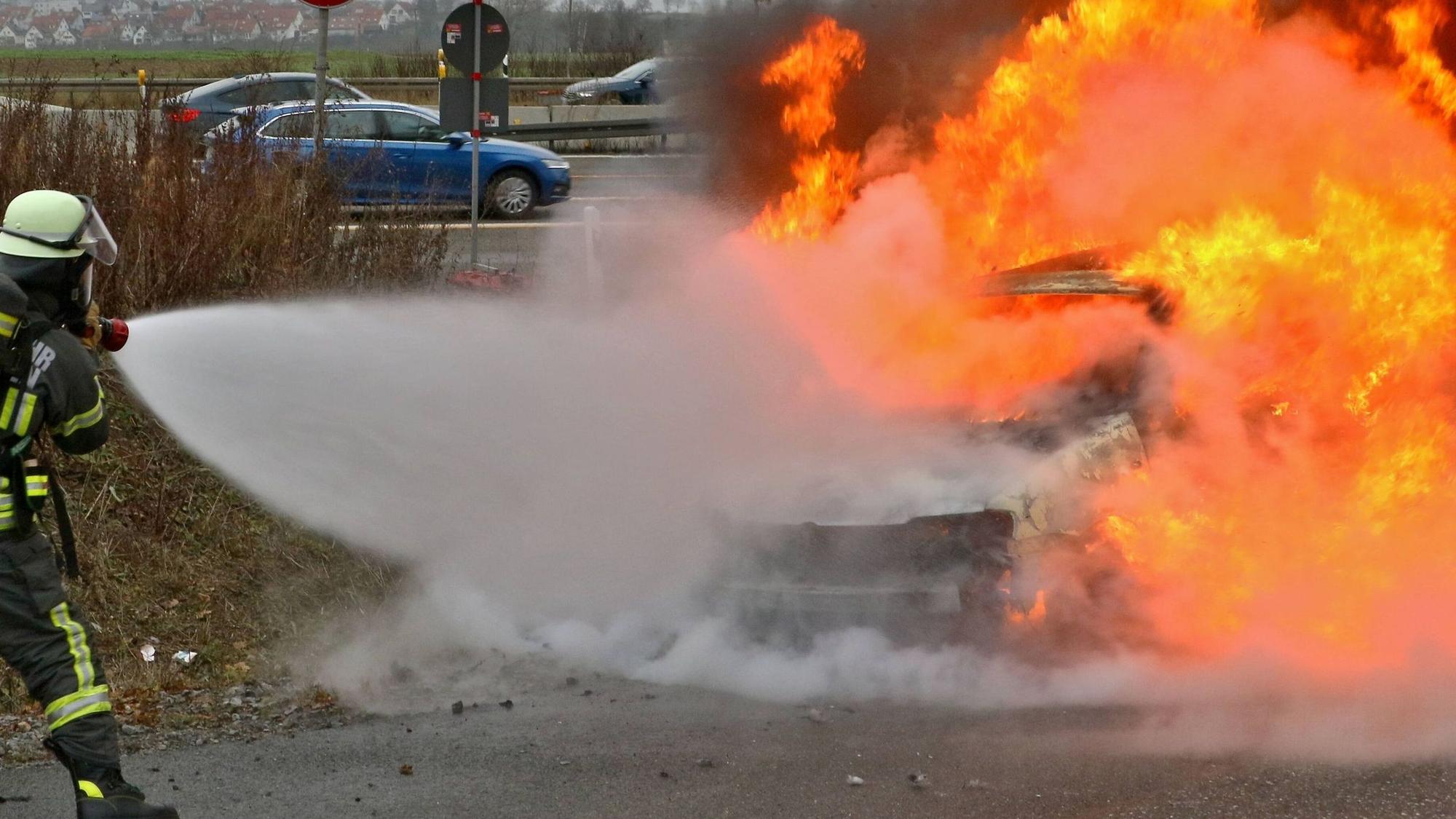 Einsatzkräfte der Feuerwehr löschen ein Fahrzeug (Symbolfoto).