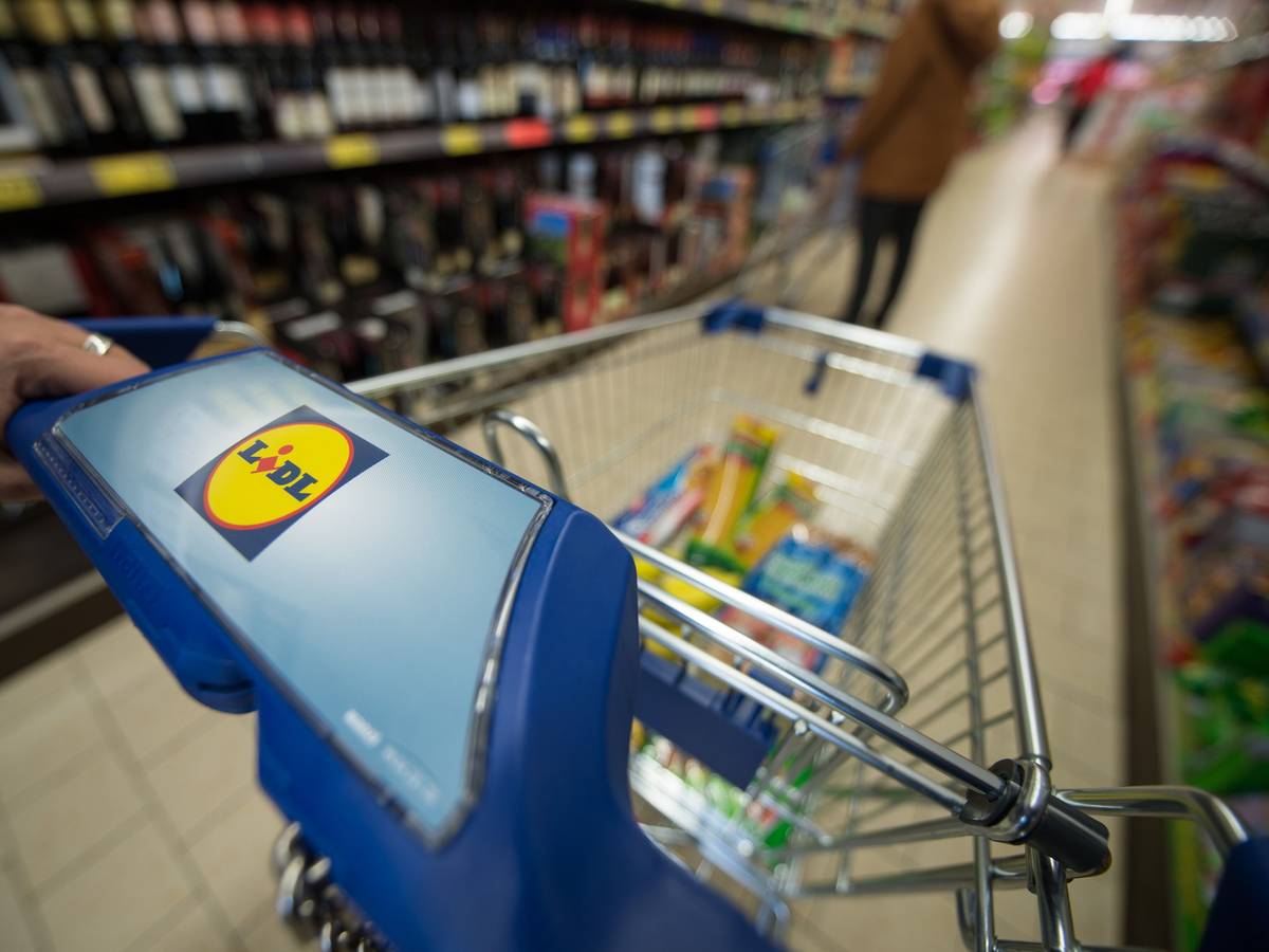 Eine Kundin schiebt einen Einkaufswagen durch einen Supermarkt.