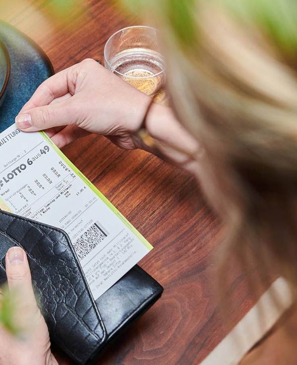Frau hält Spielschein für LOTTO 6aus49 bei WestLotto in der Hand.