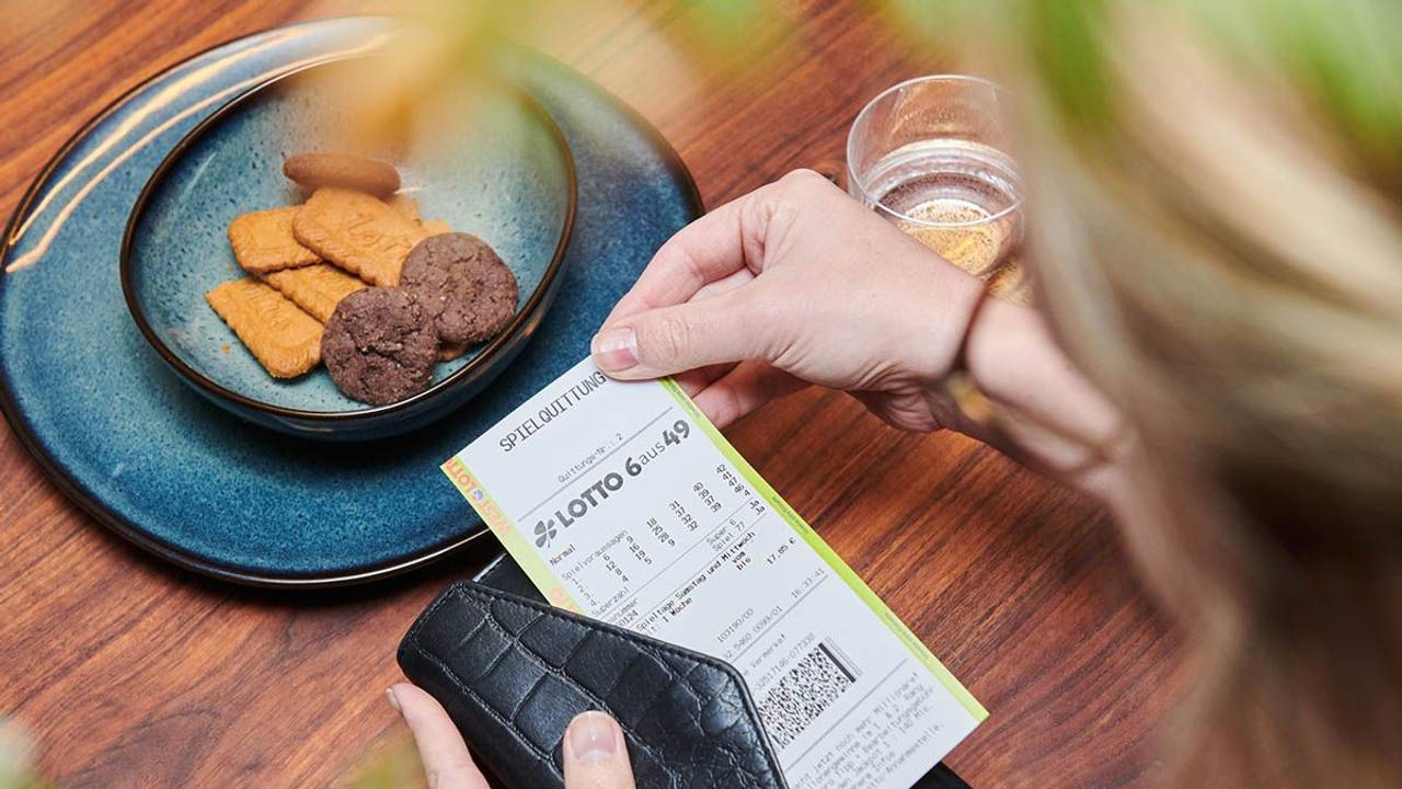 Frau hält Spielschein für LOTTO 6aus49 bei WestLotto in der Hand.