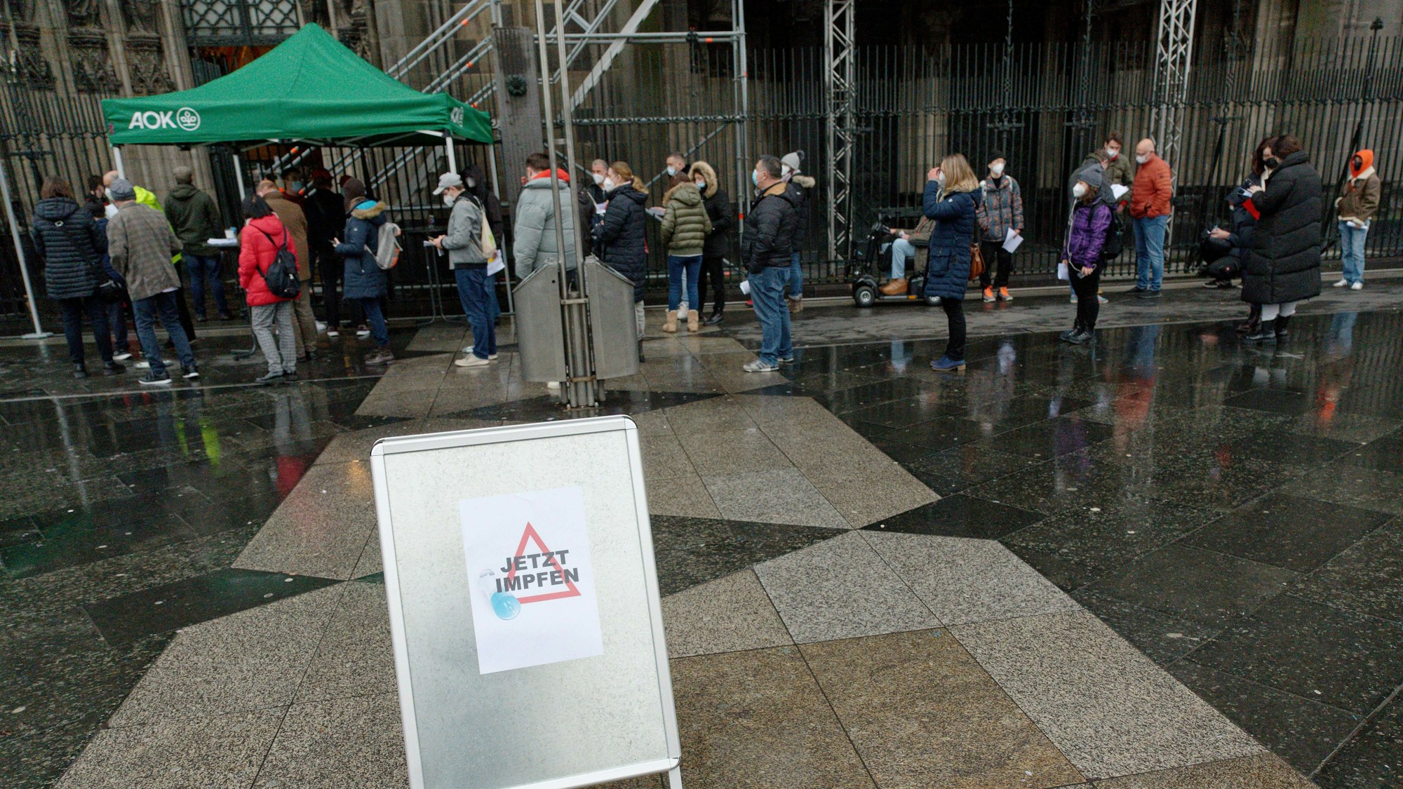 Menschen stehen bei einer Impfaktion zu Weihnachten vor dem Kölner Dom in einer Warteschlange.