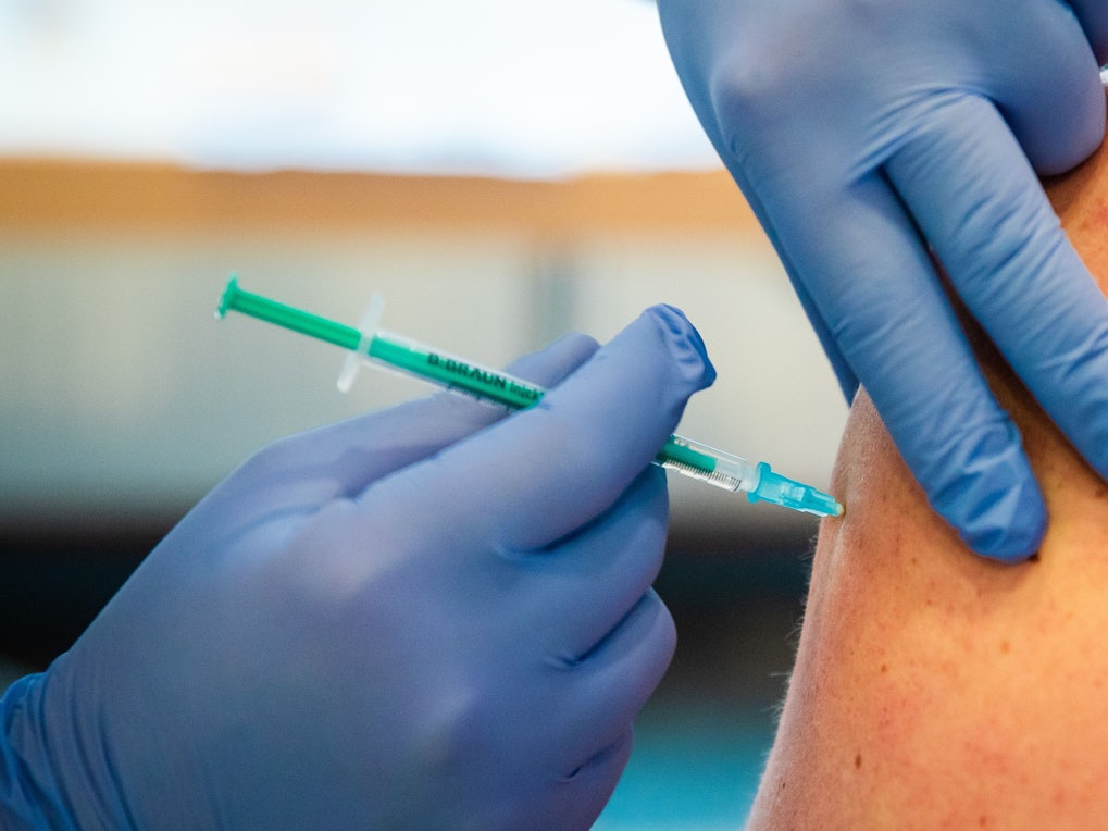 Eine Frau wird bei einer Impfaktion in einem Gemeindehaus von einem Ärzteteam gegen das Coronavirus geimpft.