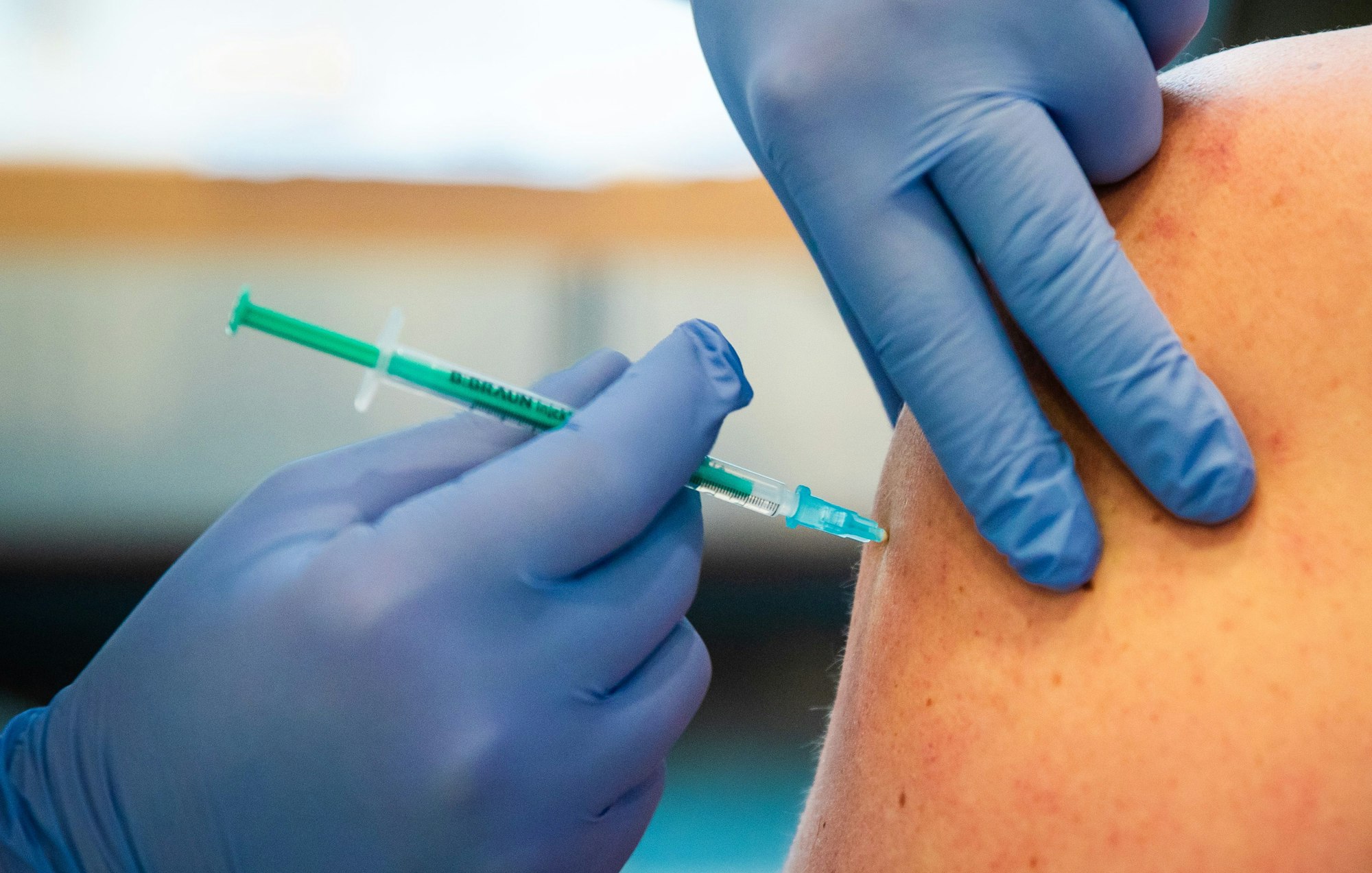 Eine Frau wird bei einer Impfaktion in einem Gemeindehaus von einem Ärzteteam gegen das Coronavirus geimpft.