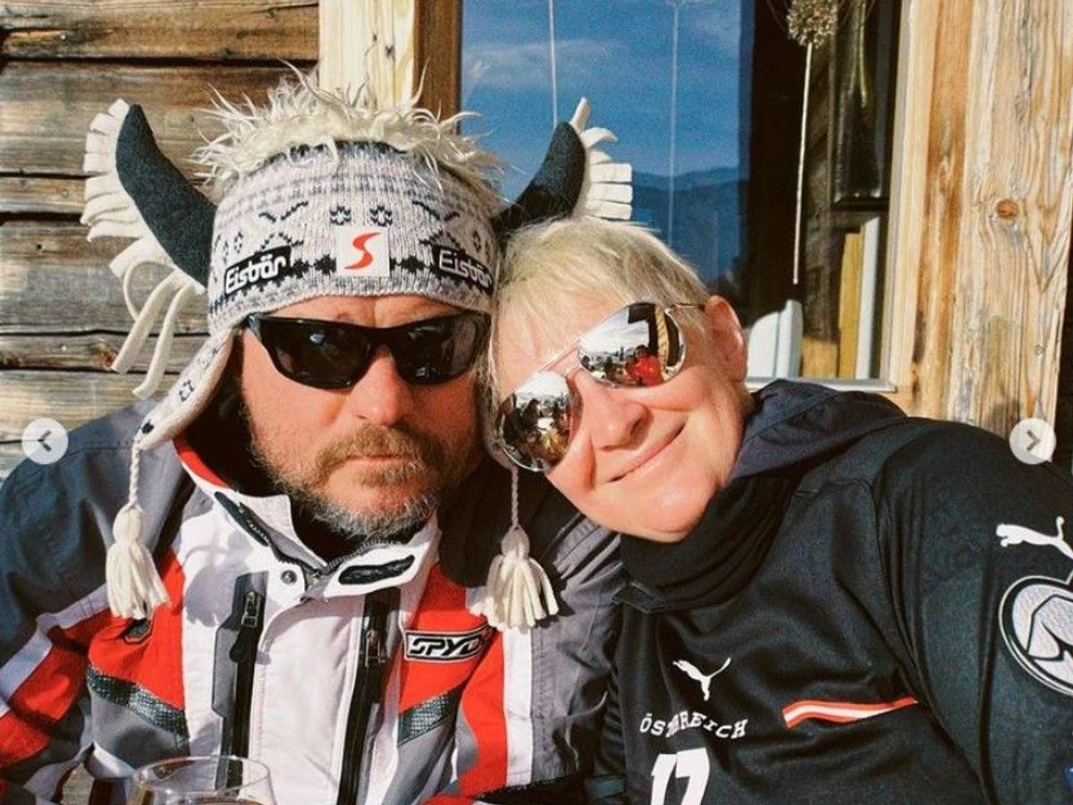 Steffen Baumgart sitzt mit seiner Frau Katja, Sonnenbrille und Hörner-Mütze an einer Skihütte in Österreich.