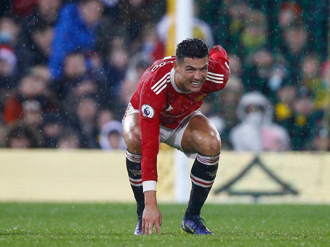 Cristiano Ronaldo hat ein schmerzverzerrtes Gesicht, geht in die Hocke und hält sich den Rücken.