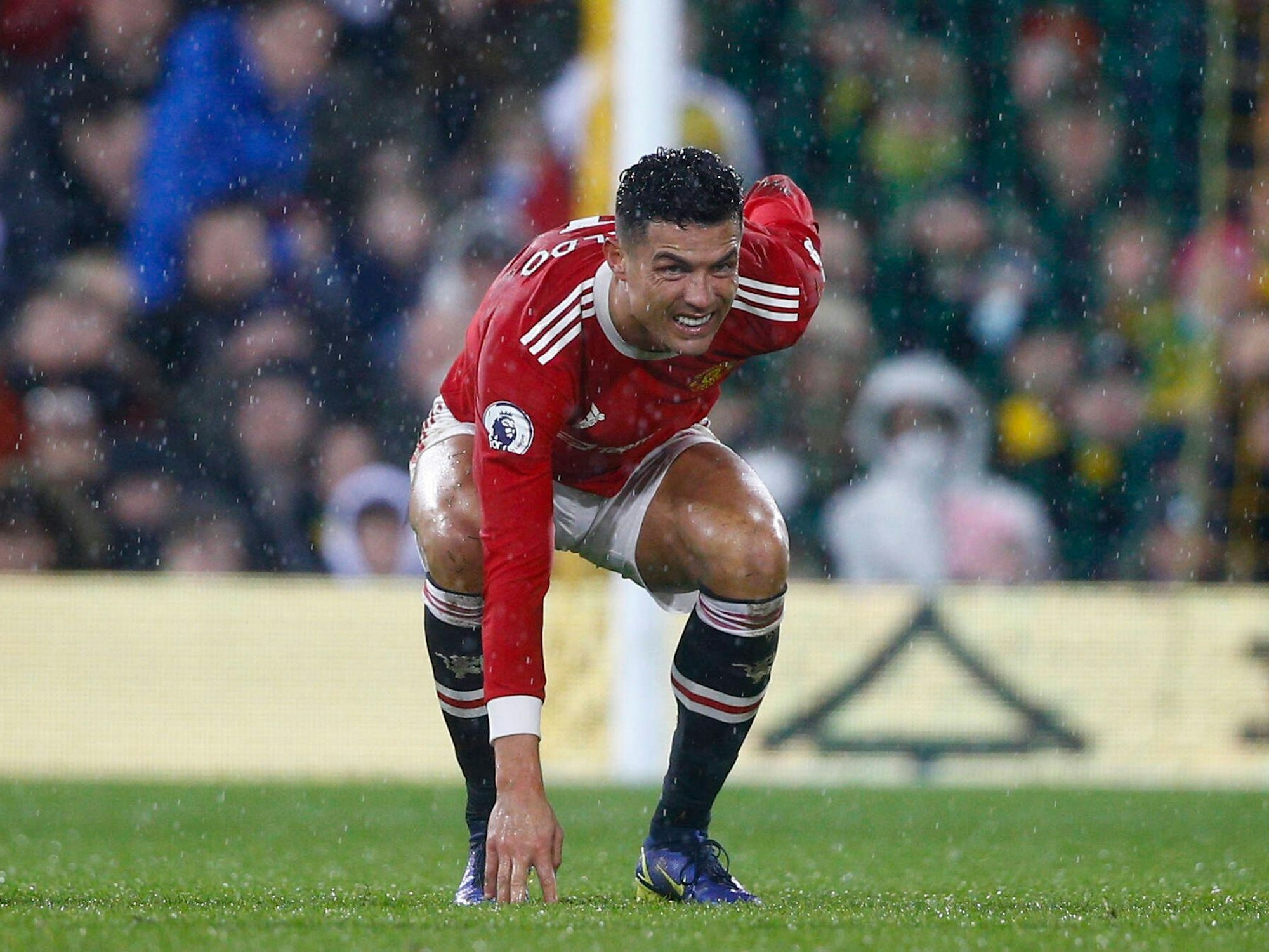 Cristiano Ronaldo hat ein schmerzverzerrtes Gesicht, geht in die Hocke und hält sich den Rücken.