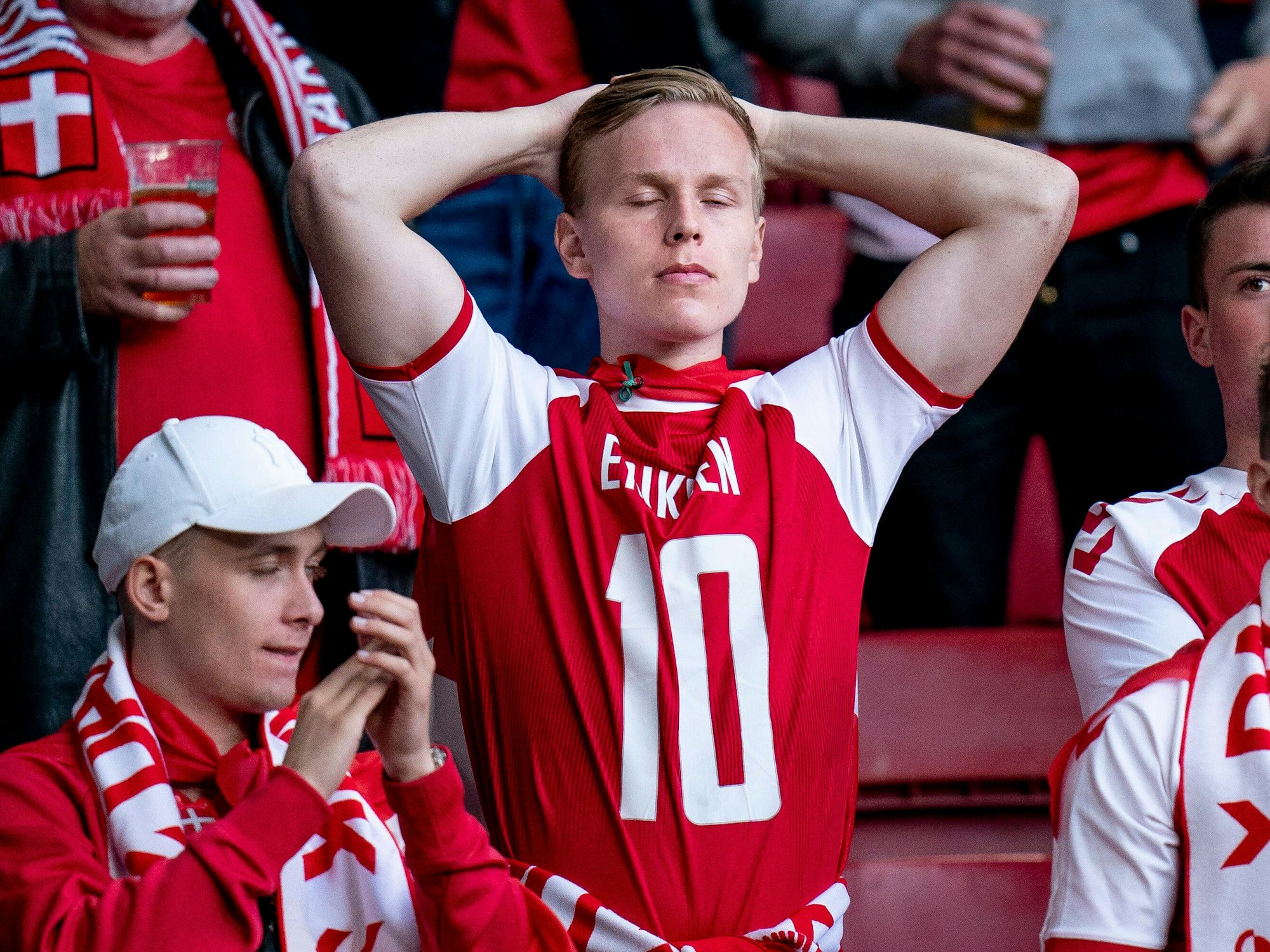 Ein schockierter Fan im umgedrehten Eriksen-Trikot schlägt die Hände über dem Kopf zusammen.