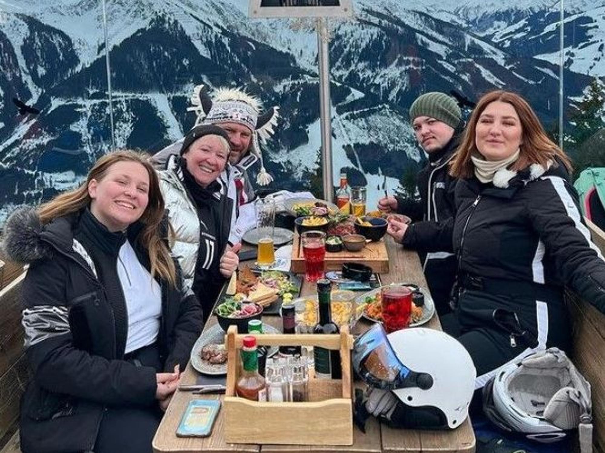 Steffen Baumgart entspannt mit seiner Familie während einer Brotzeit vor einer Skihütte.