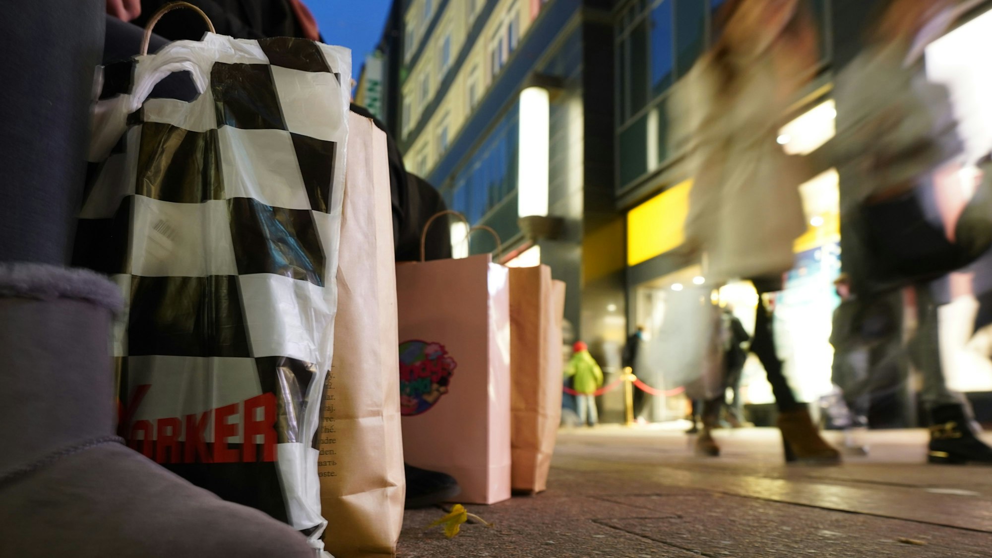 Eine Passantin sitzt mit ihren Einkaufstüten auf einer Sitzbank in der Innenstadt.