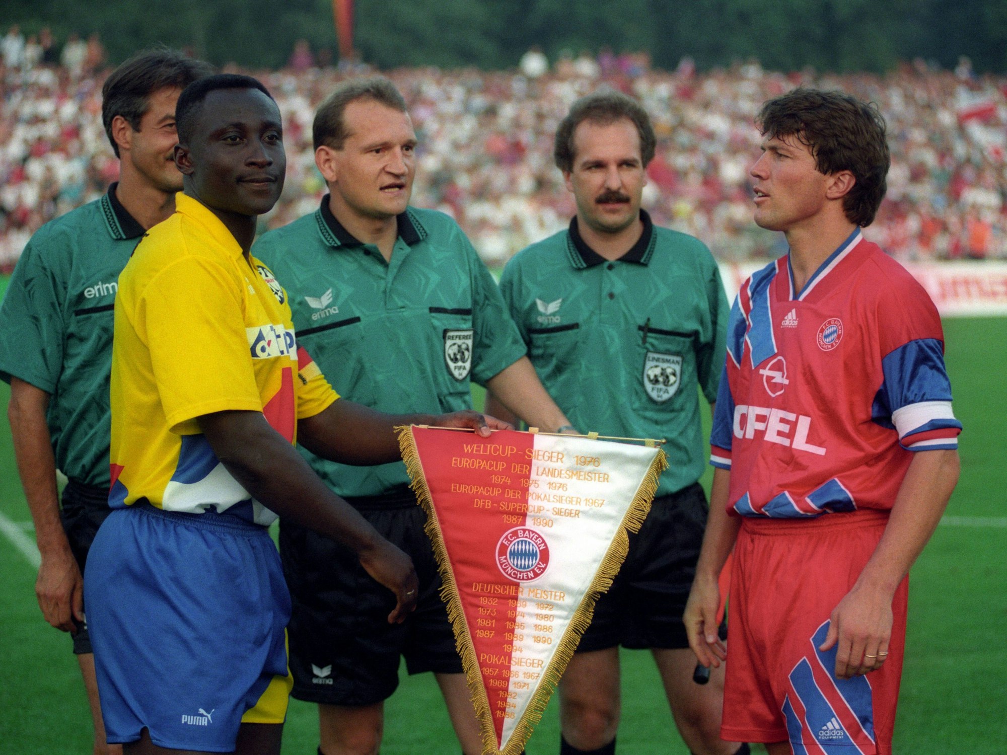 Anthony Yeboah nimmt einen Bayern-Wimpel von Lothar Matthäus entgegen.