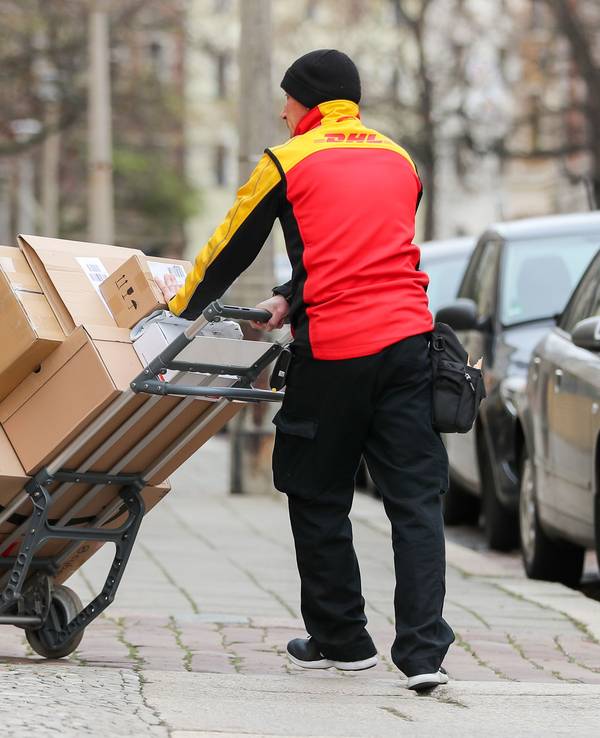 Ein DHL-Paketzusteller geht mit einer Sackkarre voll Pakete zu einem Haus im Paulusviertel. Das Bild wurde am 11. Dezember 2019 aufgenommen.