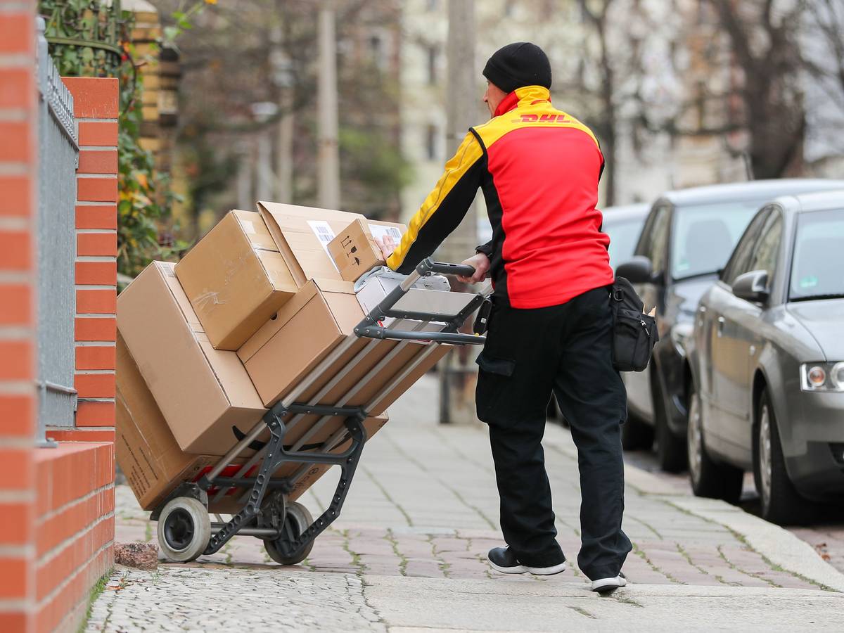 Ein DHL-Paketzusteller geht mit einer Sackkarre voll Pakete zu einem Haus im Paulusviertel. Das Bild wurde am 11. Dezember 2019 aufgenommen.