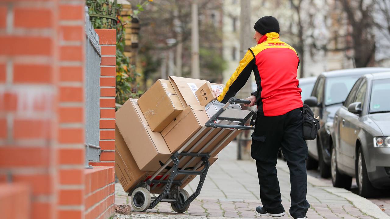 Ein DHL-Paketzusteller geht mit einer Sackkarre voll Pakete zu einem Haus im Paulusviertel. Das Bild wurde am 11. Dezember 2019 aufgenommen.