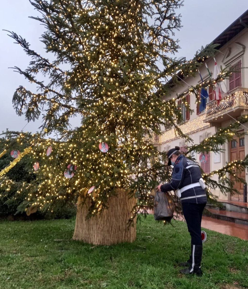 Ein Polizist entfernt am 28. Dezember 2021 „Hitler-Baumschmuck“ vom Gemeinde-Weihnachtsbaum vor dem Rathaus. Unbekannte hatten rund ein Dutzend rote Papp-Kreise mit Nazi-Abbildungen und dem Gesicht von Adolf Hitler an den Baum gehängt.