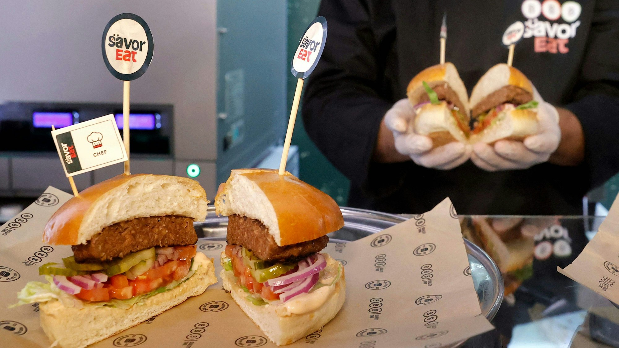 Ein Mitarbeiter präsentiert fertige Roboter-Burger.