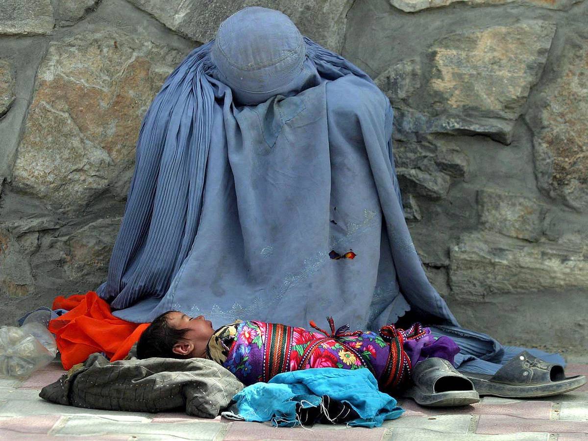 Eine Afghanin bettelt am Straßenrand um Almosen, ihr Säugling liegt vor ihr.