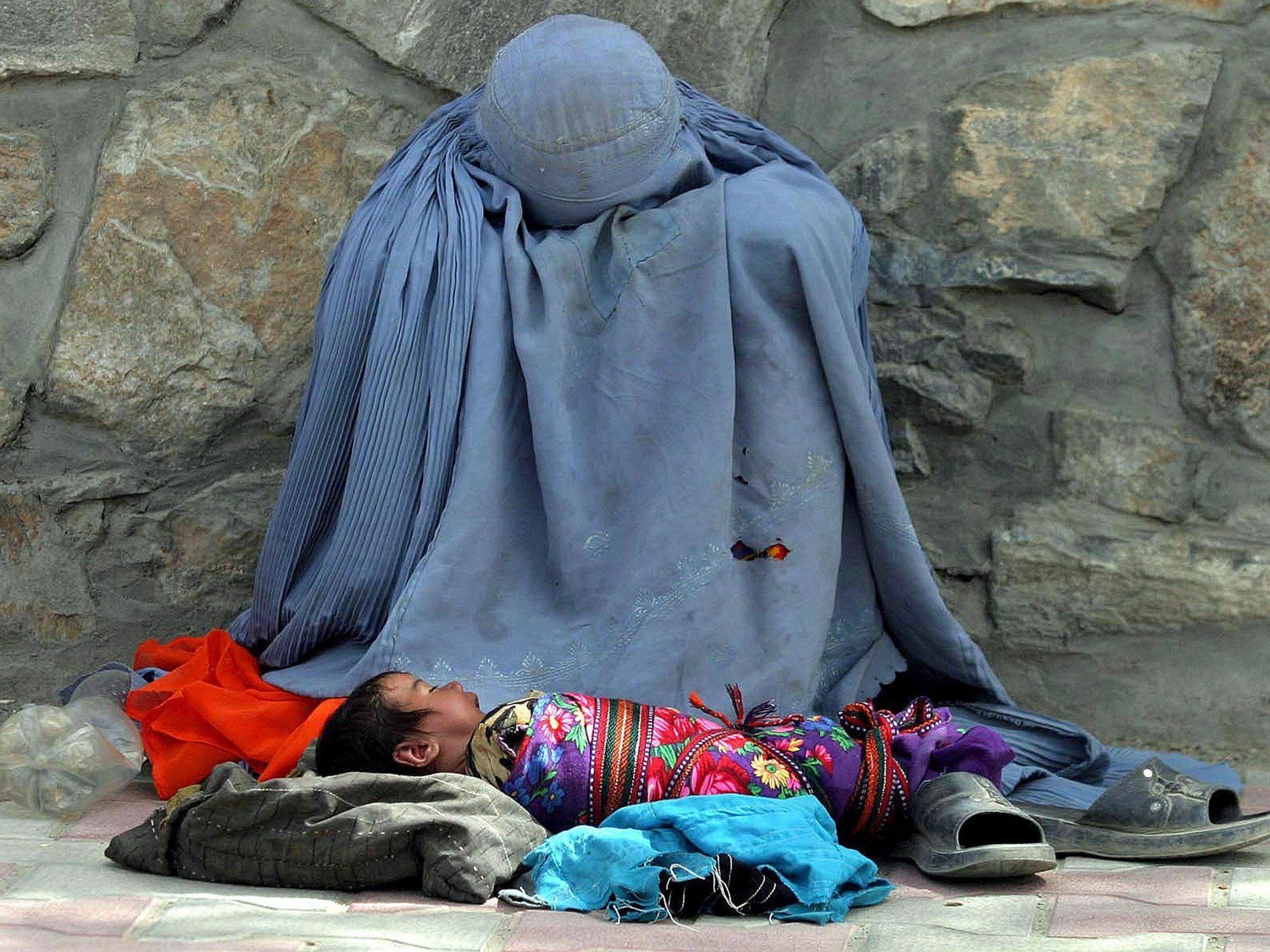 Eine Afghanin bettelt am Straßenrand um Almosen, ihr Säugling liegt vor ihr.