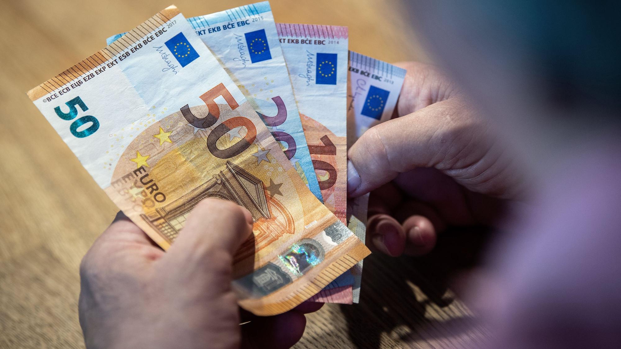 Ein Mann sitzt an einem Tisch und zählt Geld.