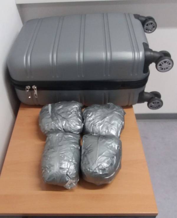 Vier Päckchen mit Drogen liegen vor einem Koffer auf einem Tisch.