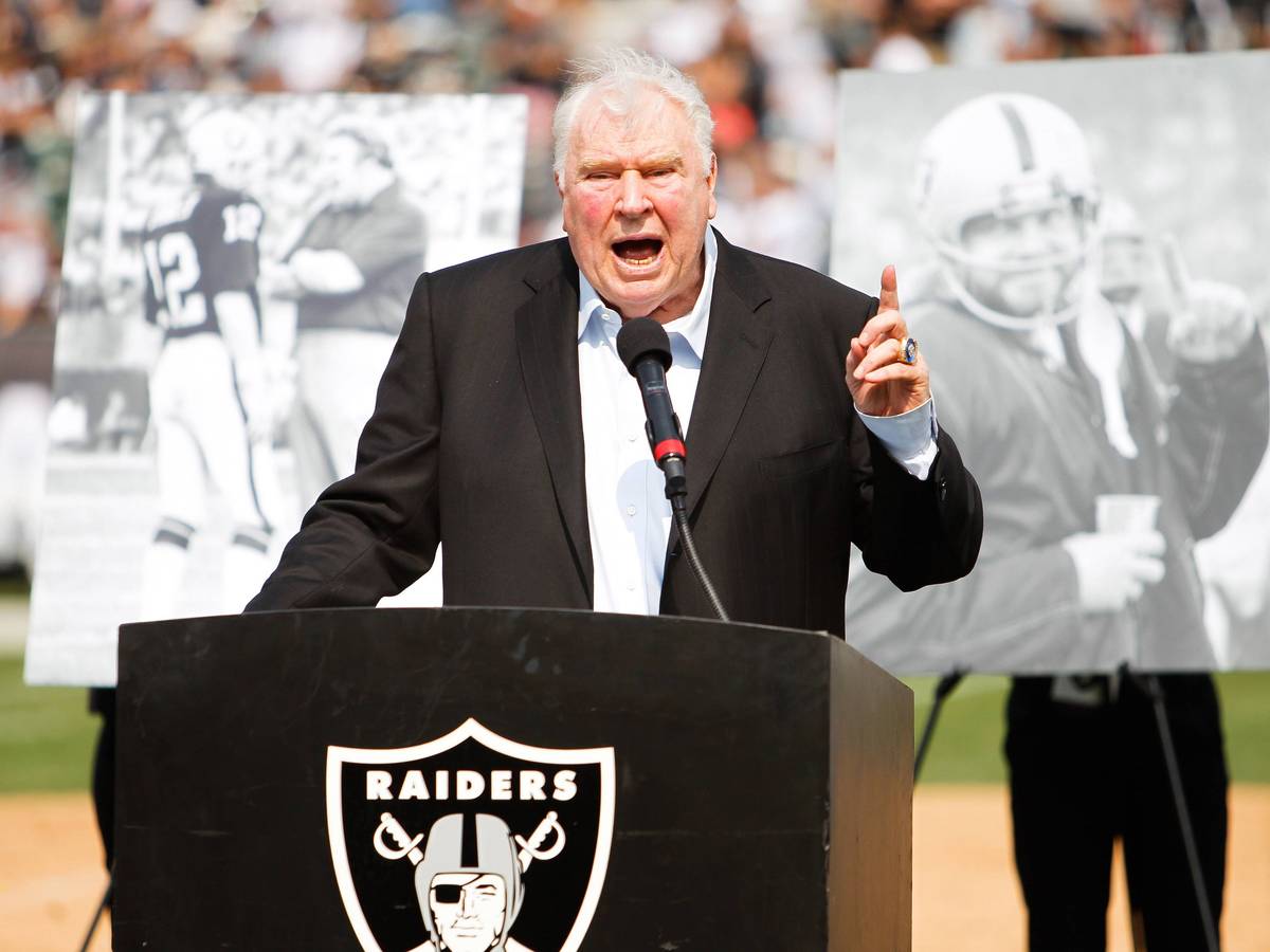 John Madden steht auf einem kleinen Podest, auf dem das Wappen der Las Vegas Raiders abgebildet ist.
